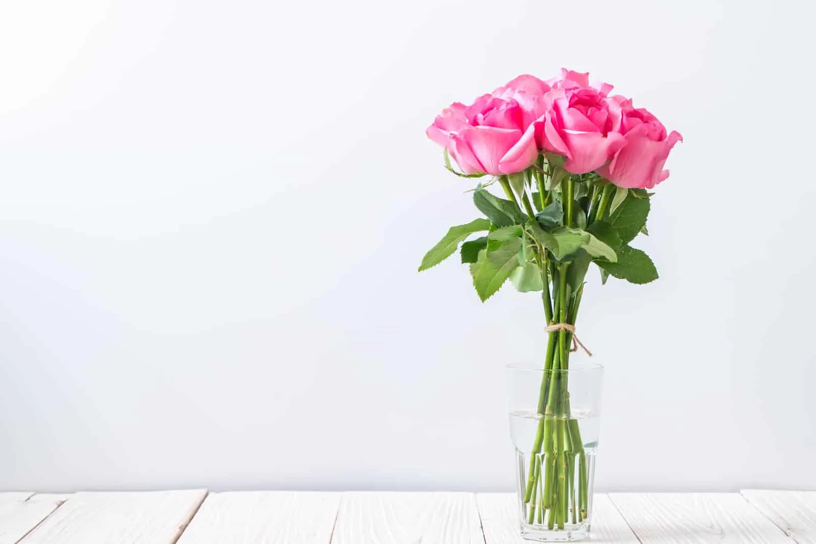 pink roses in vase on wooden table
