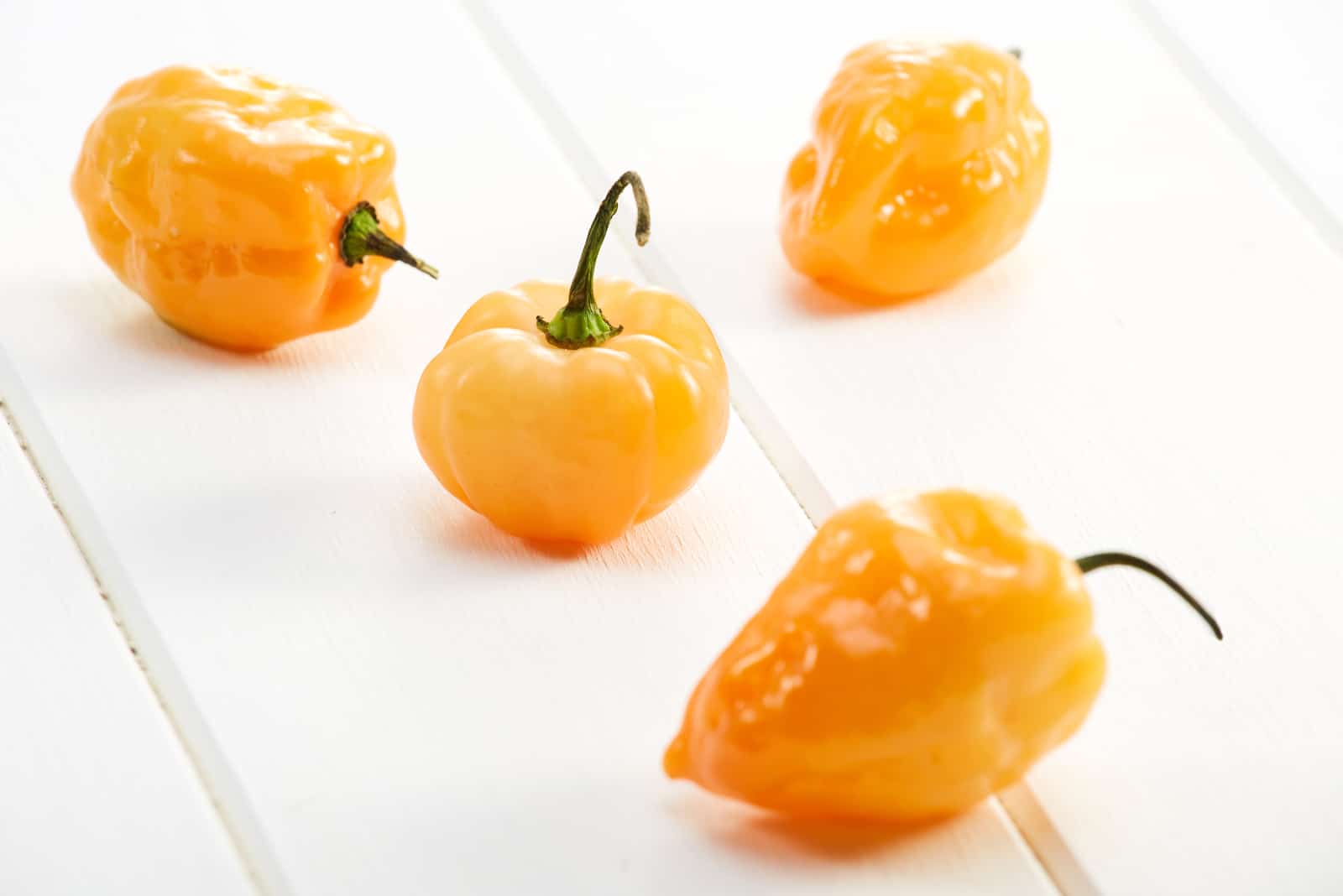 Yellow Habanero hot chili peppers on a white wooden table