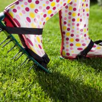 Woman wearing spiked lawn revitalizing aerating shoes