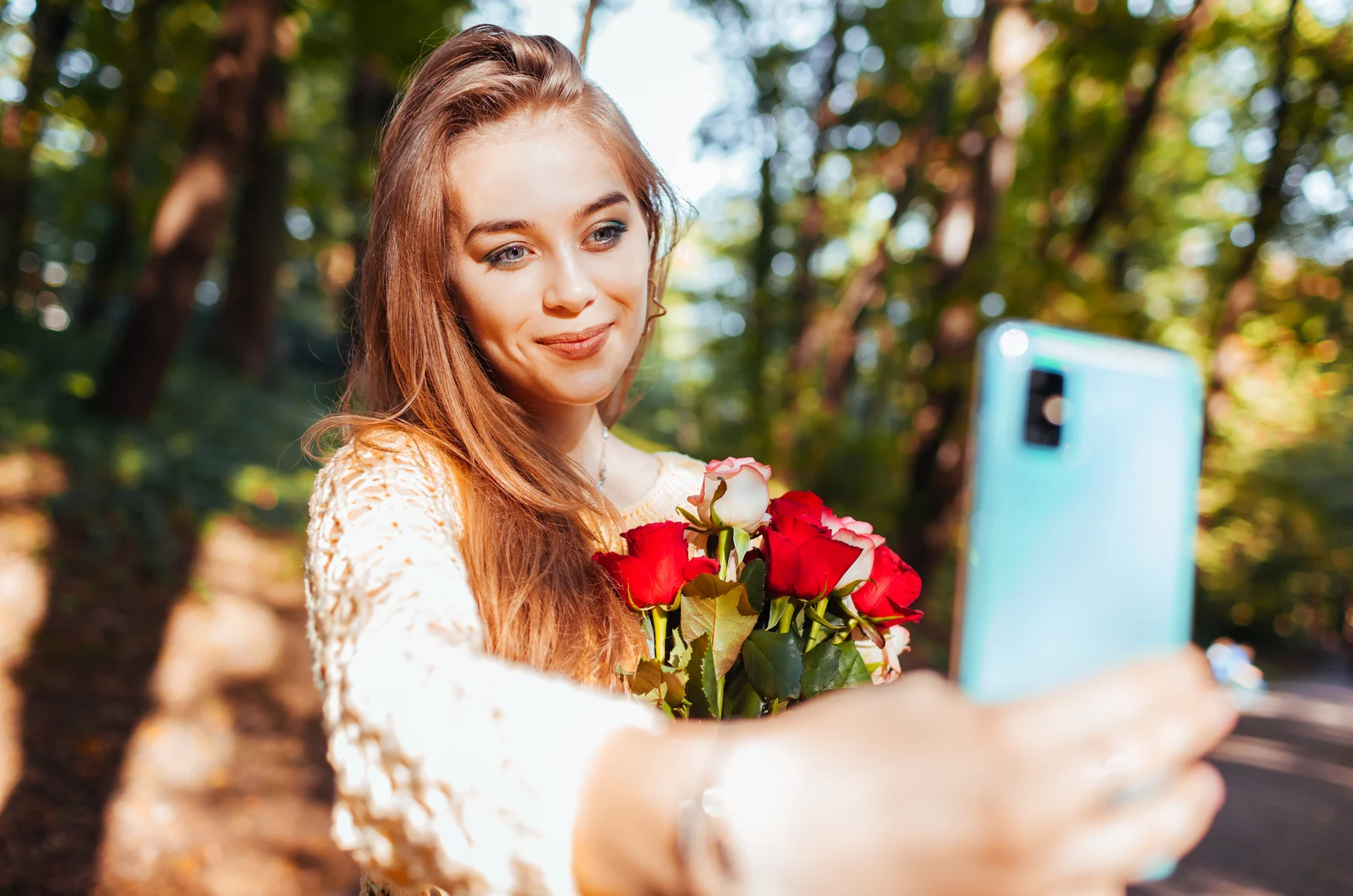 a woman with long brown hair takes a picture with a bouquet of roses