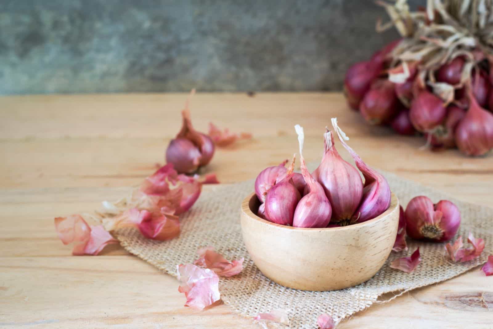 shallots in bowl on old wooden table 