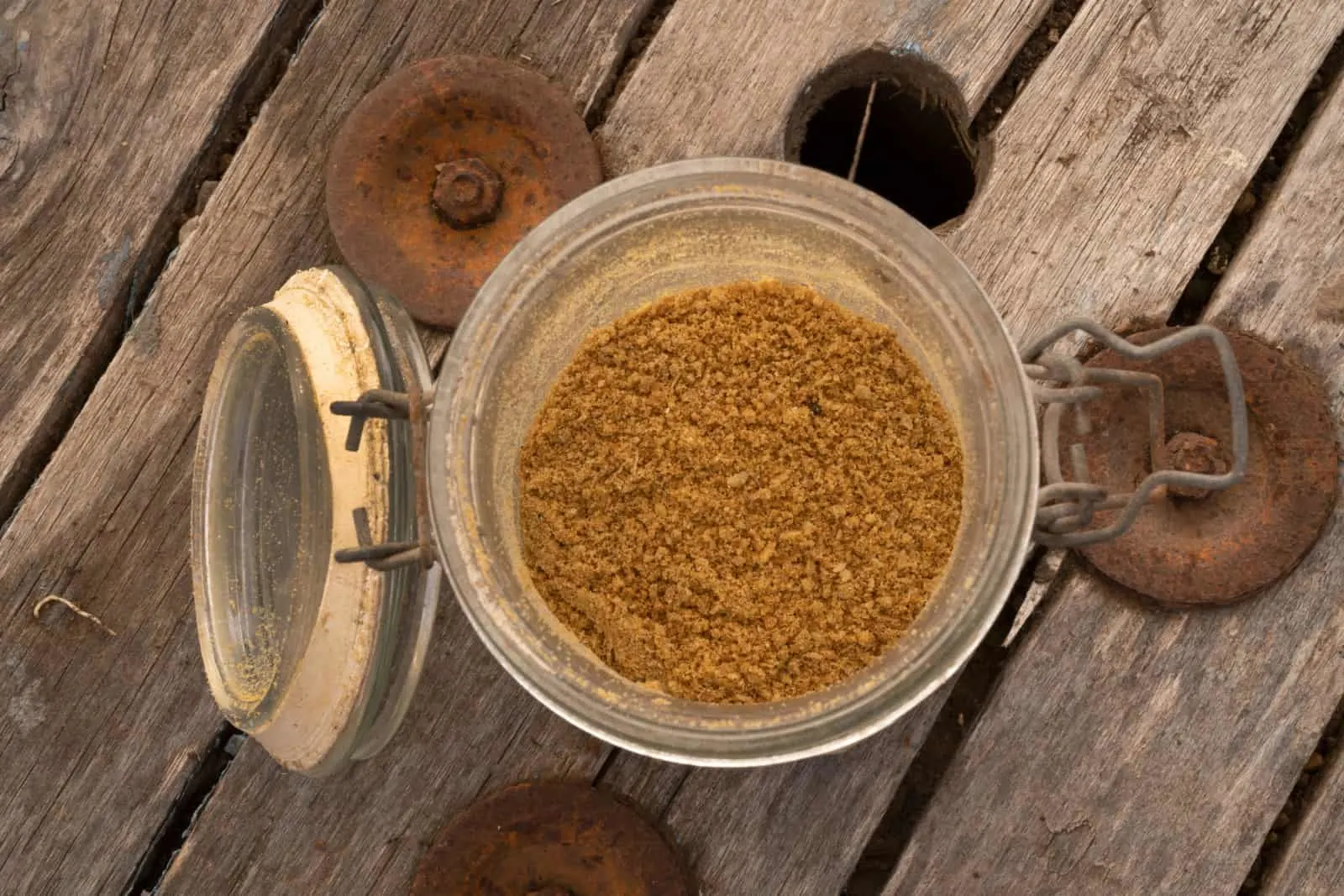 top closeup view of bone meal in a glass jar on the wooden table