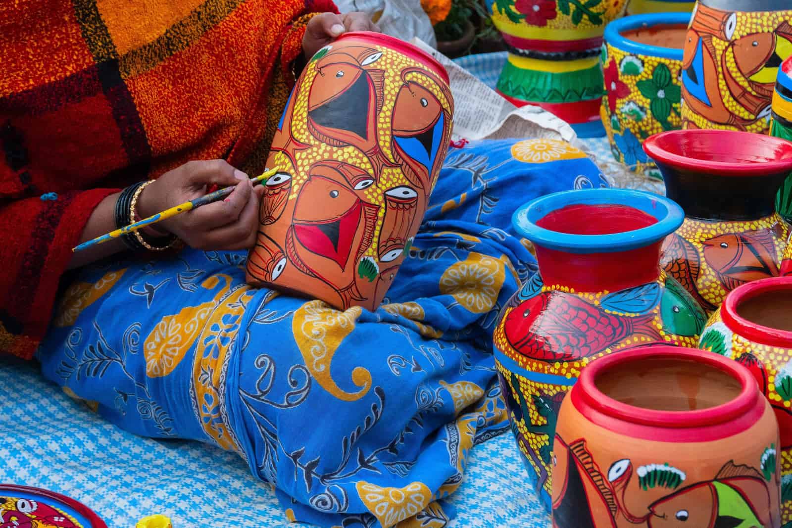 Female Indian artist painting colorful terracotta pots