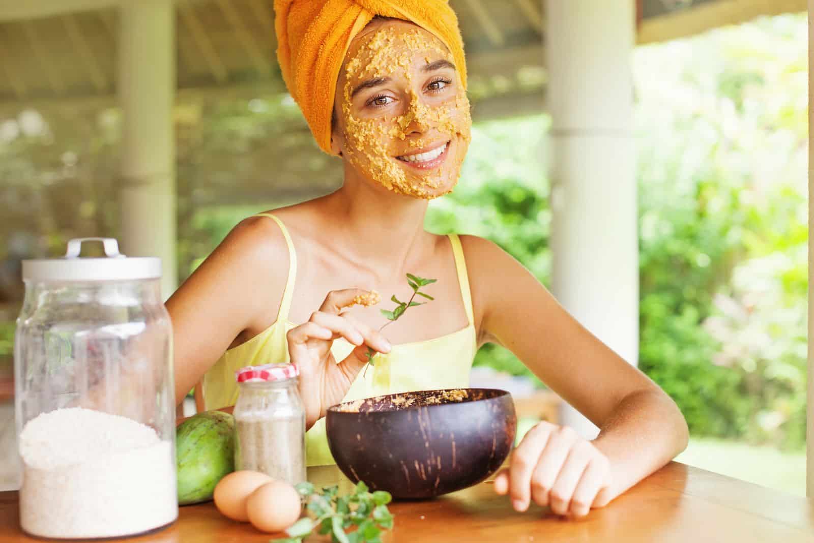 a smiling woman is sitting at the table with a mask on her face