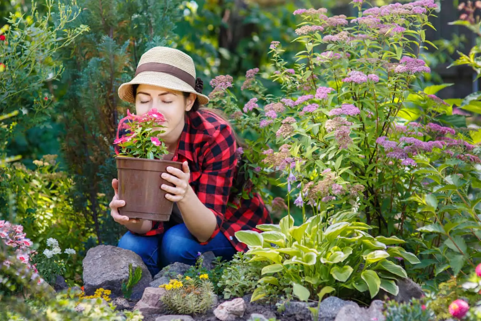 young woman gardener smelling flowers in pot with eyes closed