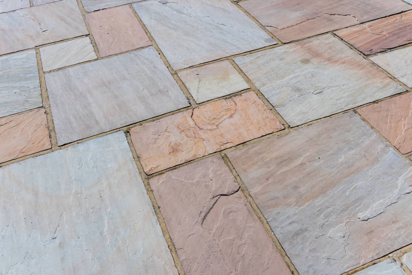 Abstract texture of red, yellow and grey toned Indian sandstone paving