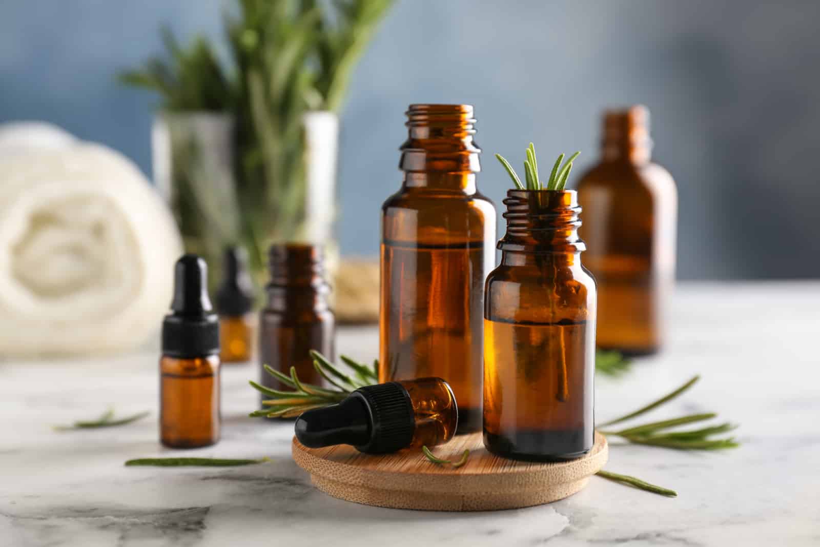 Bottles with rosemary essential oil on table
