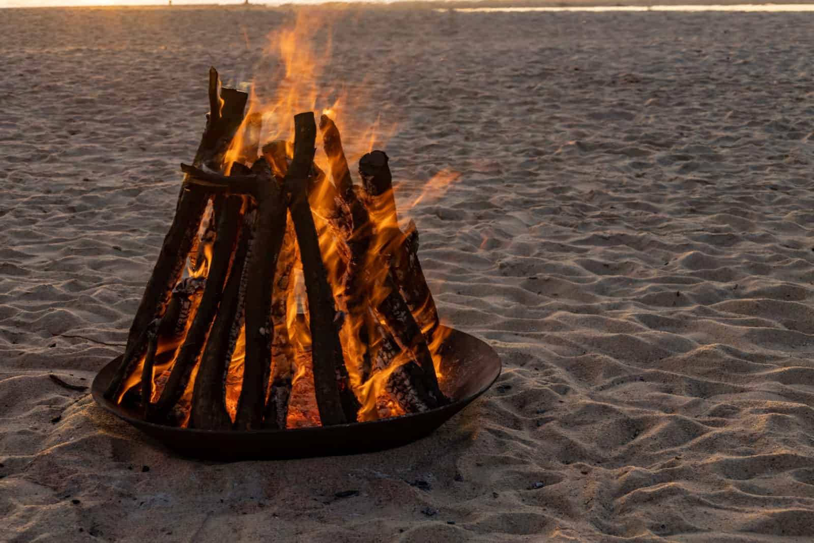 Campfire on a beach during sunset.