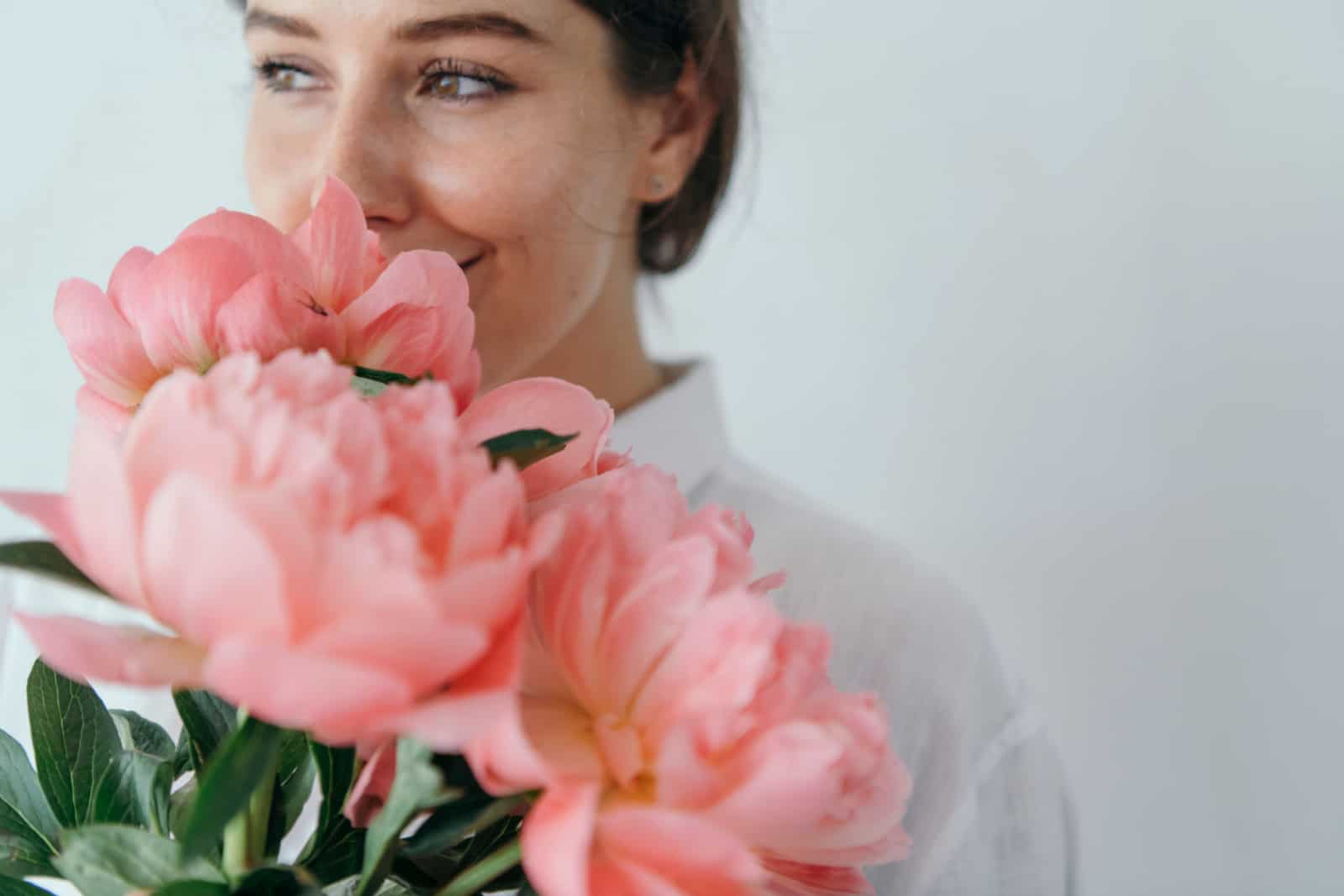 Happy woman smelling a bouquet of coral sunset peony, her birth month flower