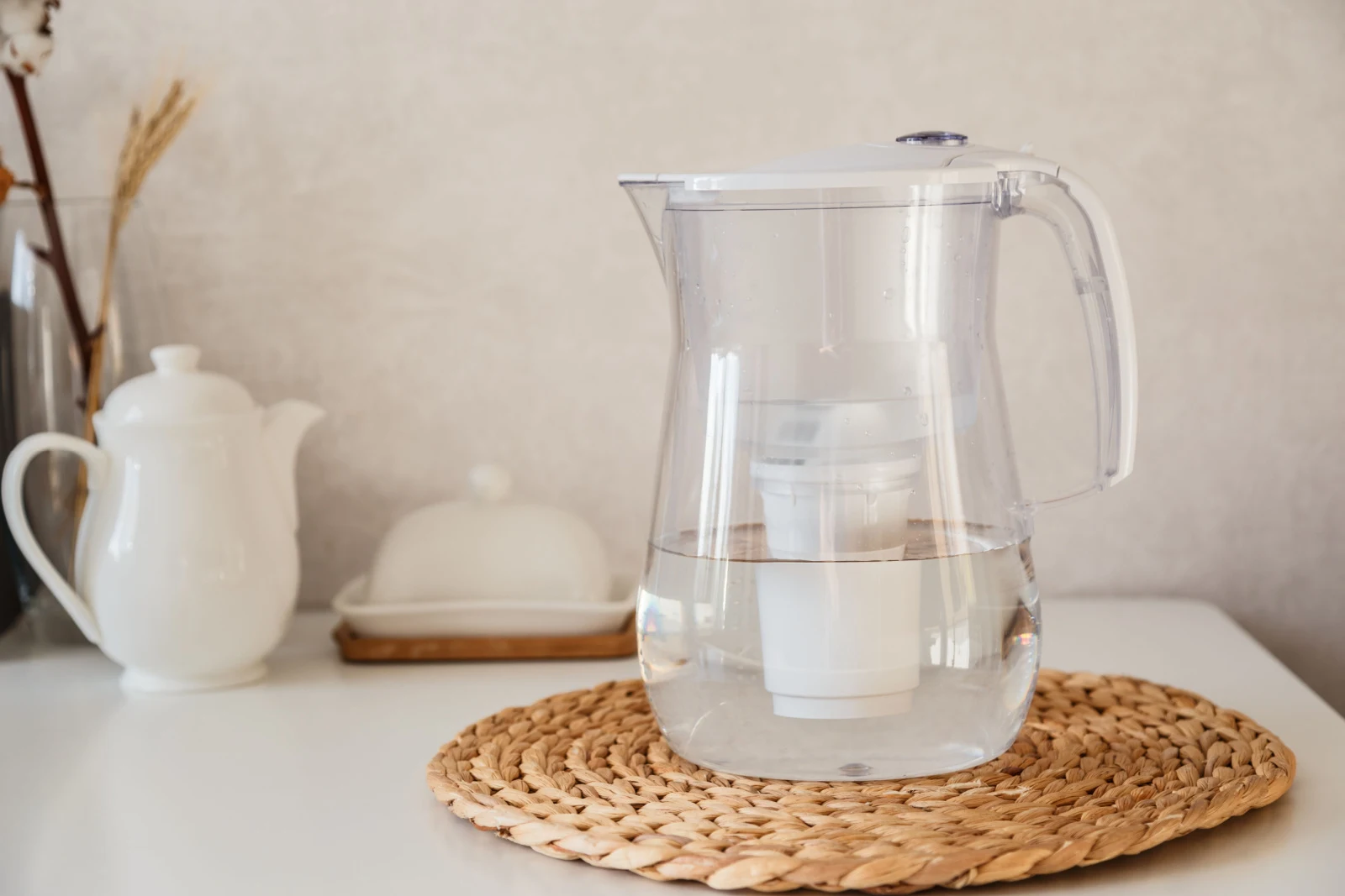 Glass and jug with fresh water on table in the kintchen