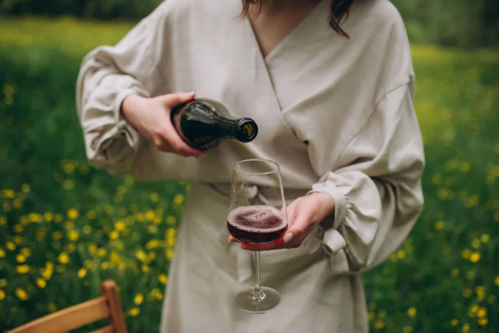 Pouring red wine into a glass in the garden.