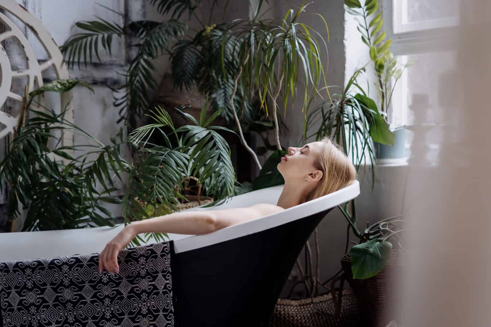 Relaxed and serene young woman taking bath in boho chic apartment