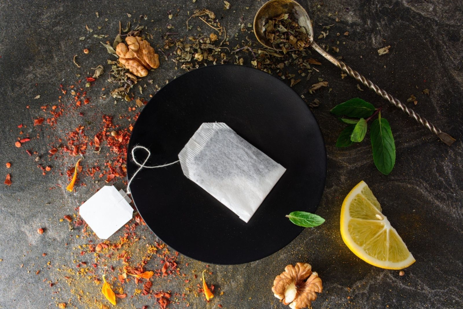 tea bag on plate with herbs and lemon