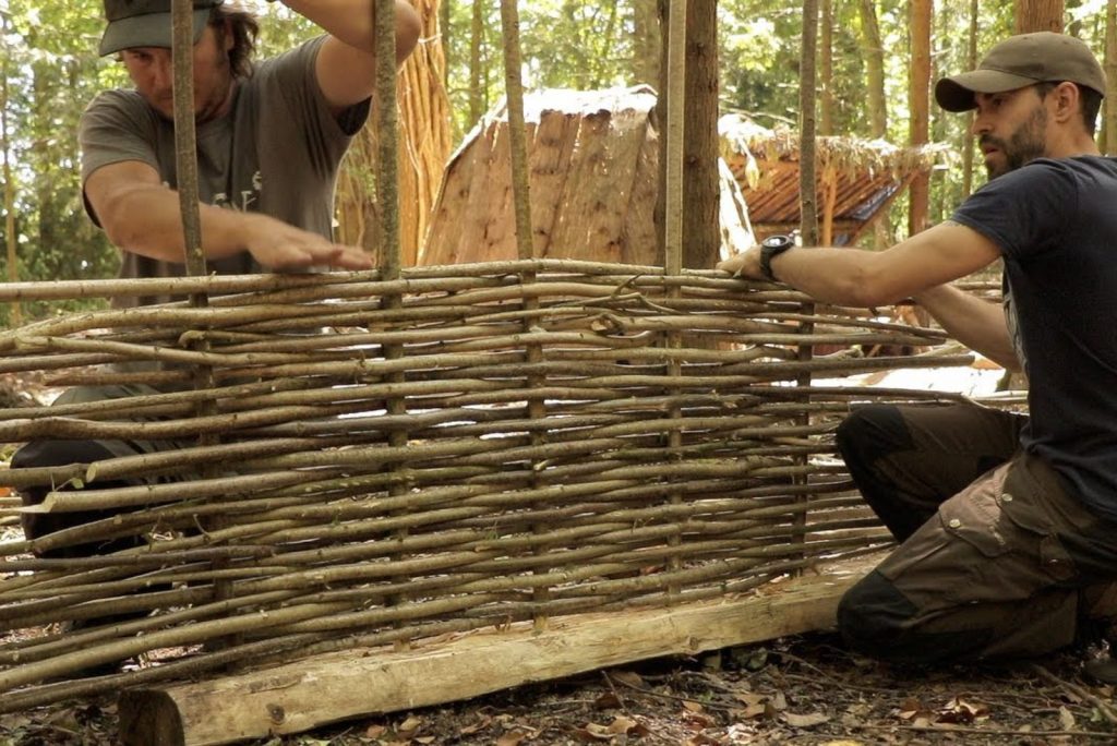 two men are making a wicker fence