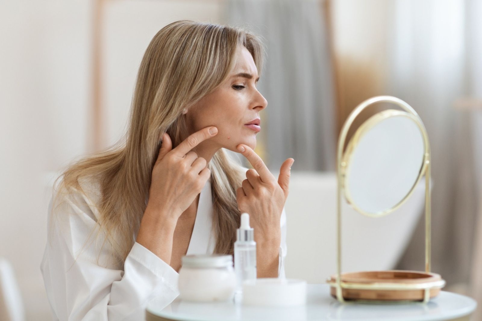 woman looking at pimple in the mirror