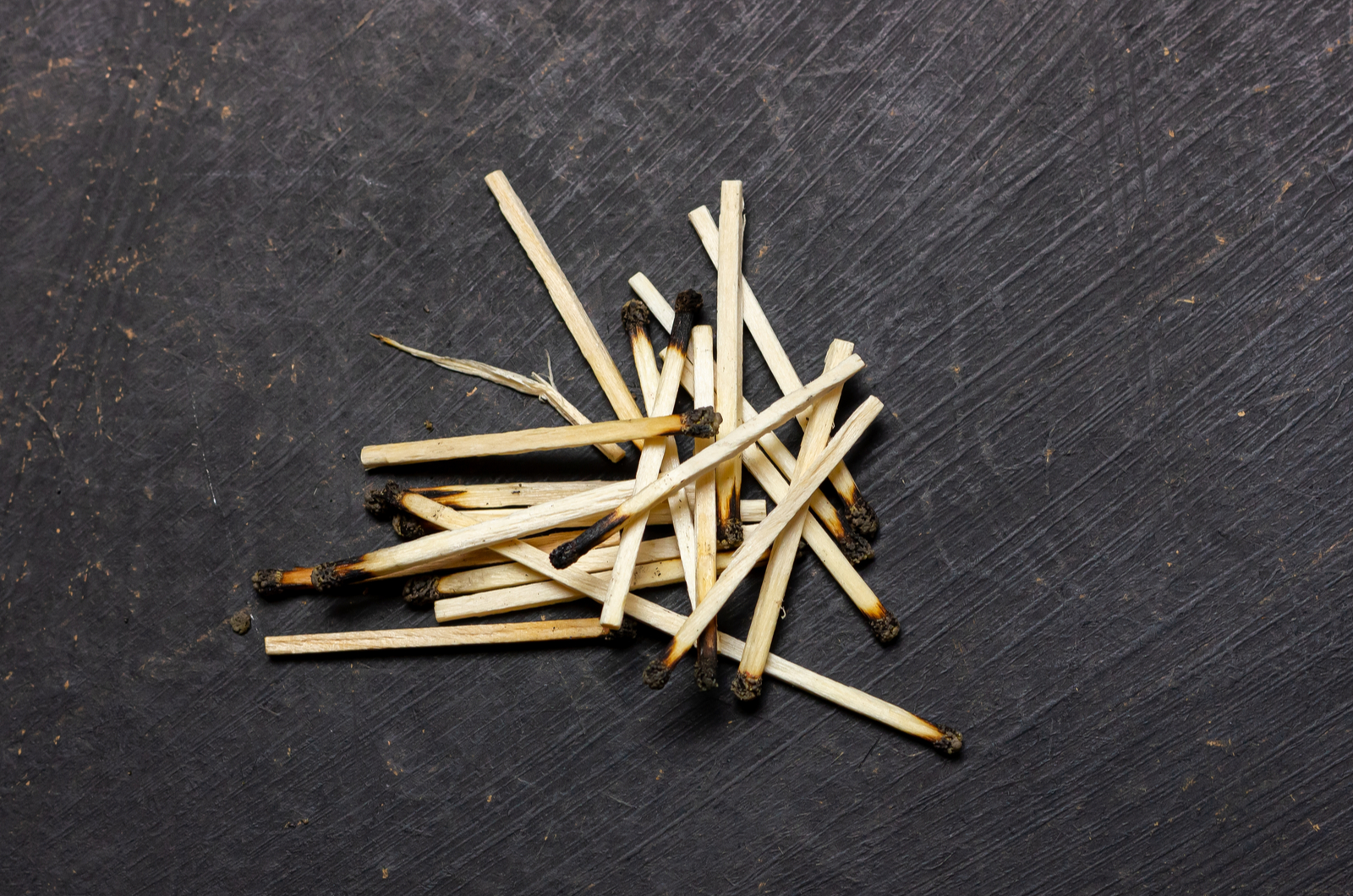 burnt matches in a pile on a black background