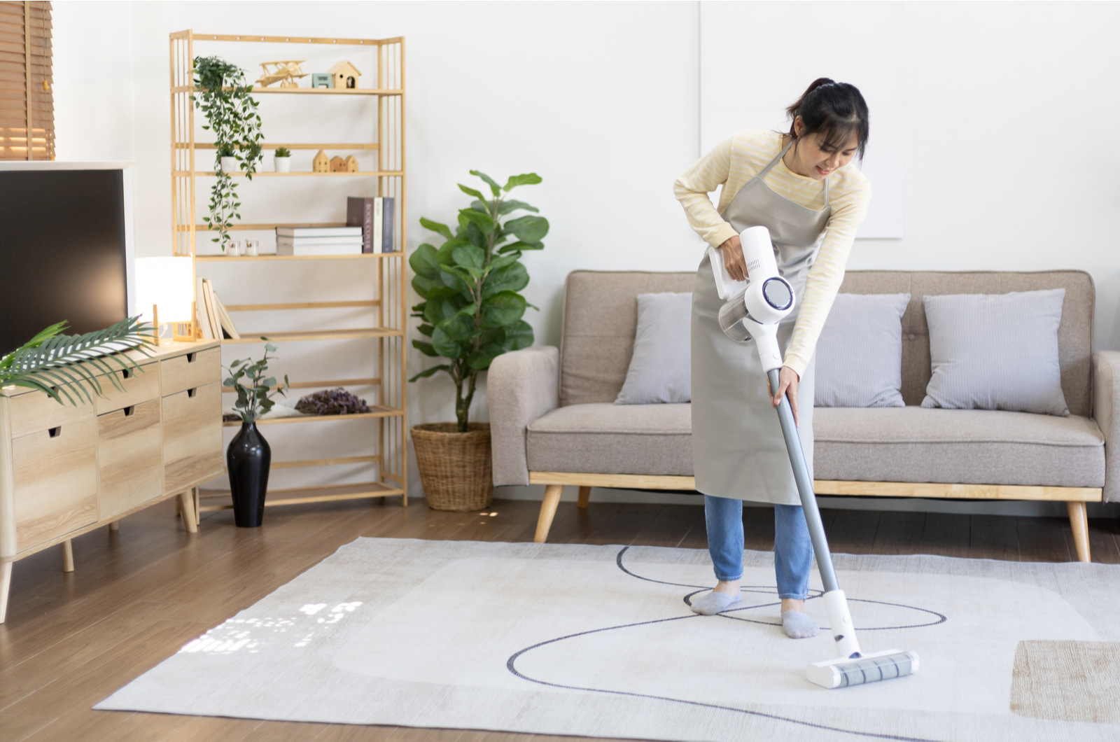 woman vacuuming the floor and carpet in her living room