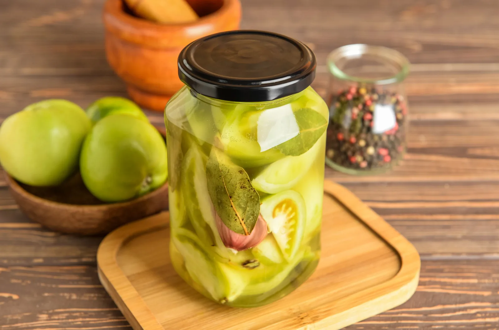 Jar with canned green tomatoes on wooden background