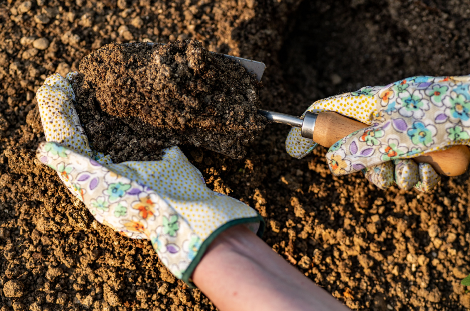 hands with gloves digging soil