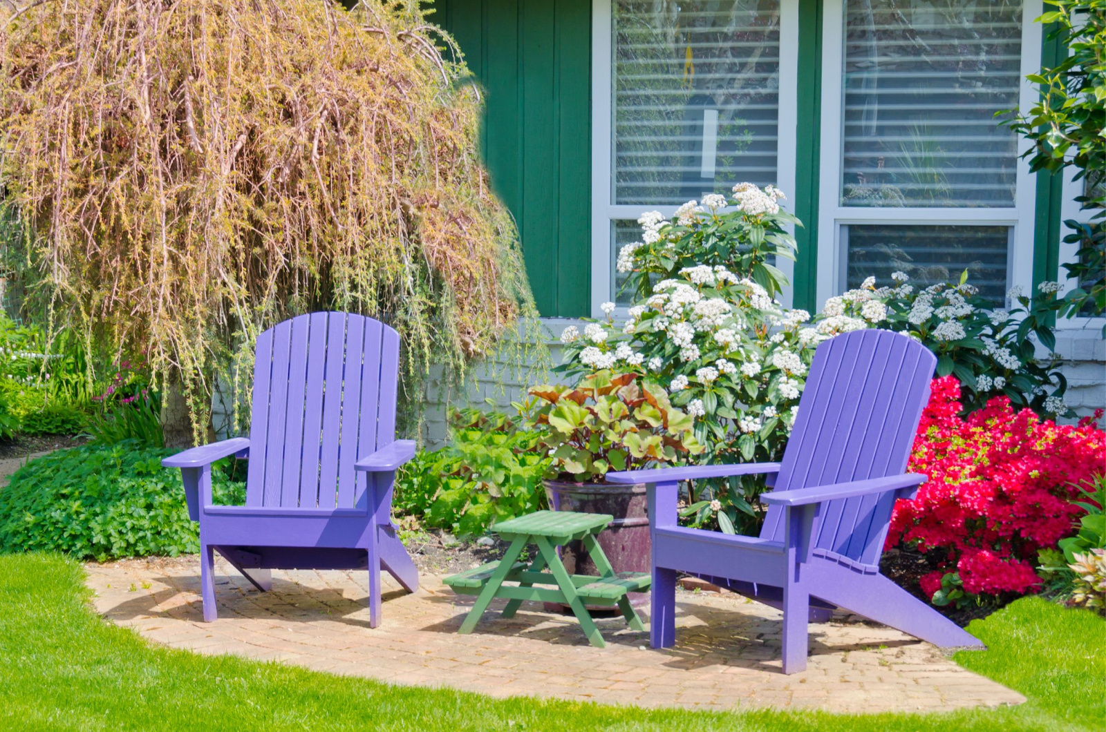 Two wooden lawn chairs in the front yard