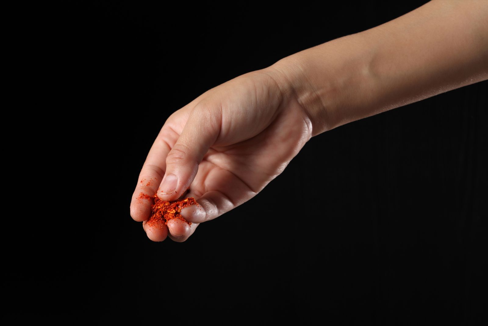 a woman holds a Cayenne Pepper between her fingers