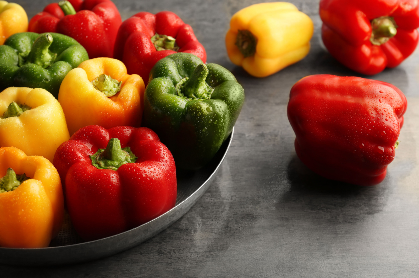 Red, green and yellow sweet bell peppers on table