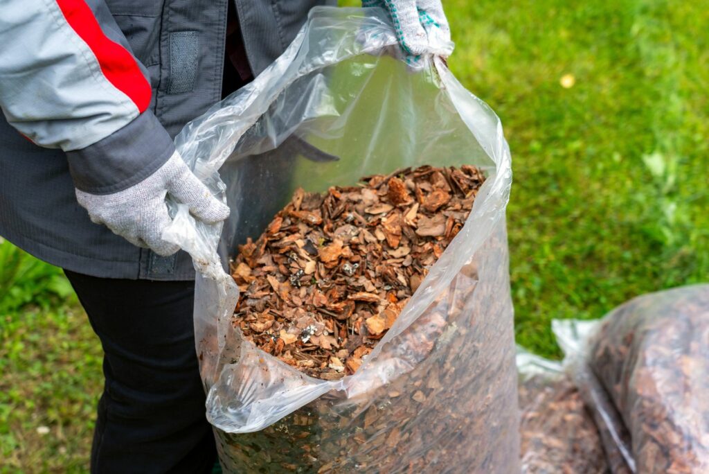 Woman gardener holds open bag of mulch in her hands