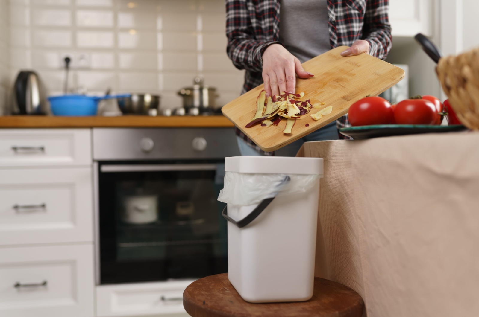 Woman throwing food peels into bokashi composter