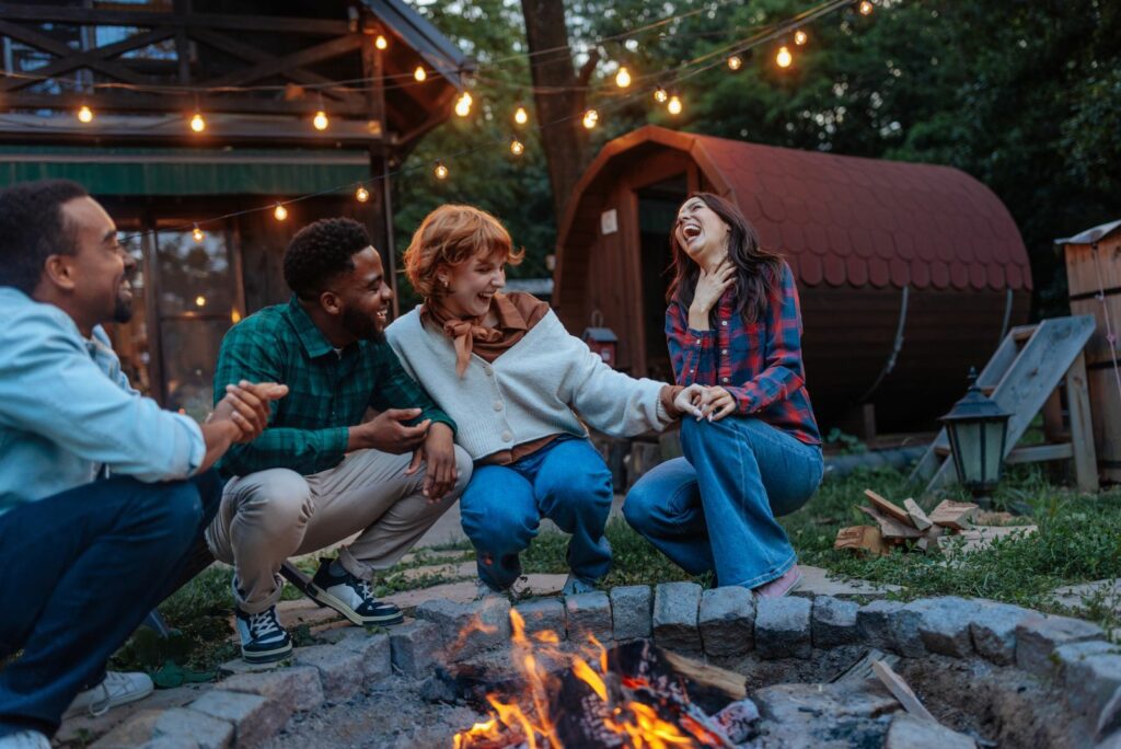 Smiling people sitting by the fire in the yard