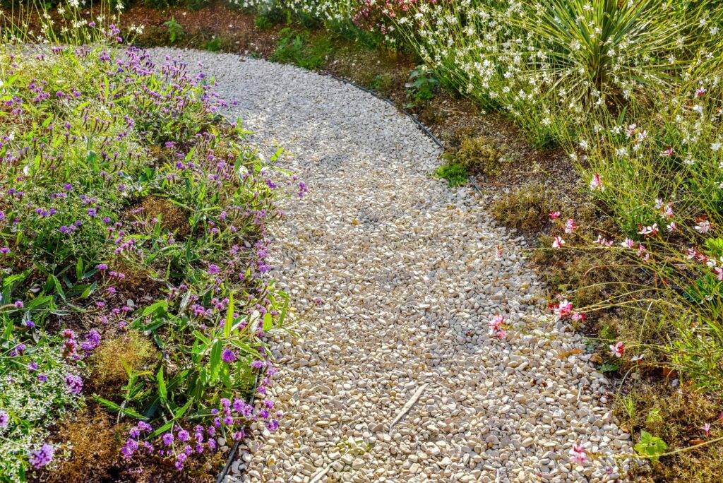 pretty alley of small pebbles in the flower garden