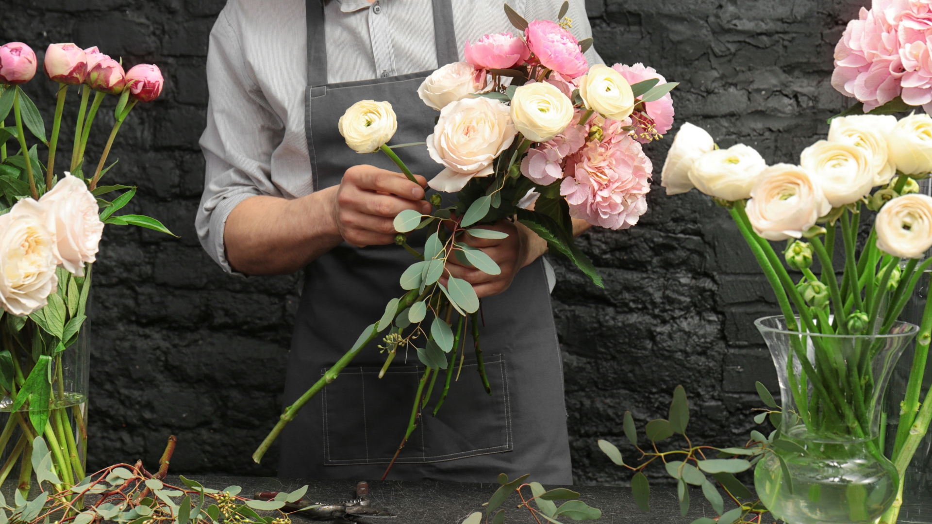 Male florist creating beautiful bouquet in flower shop, close up