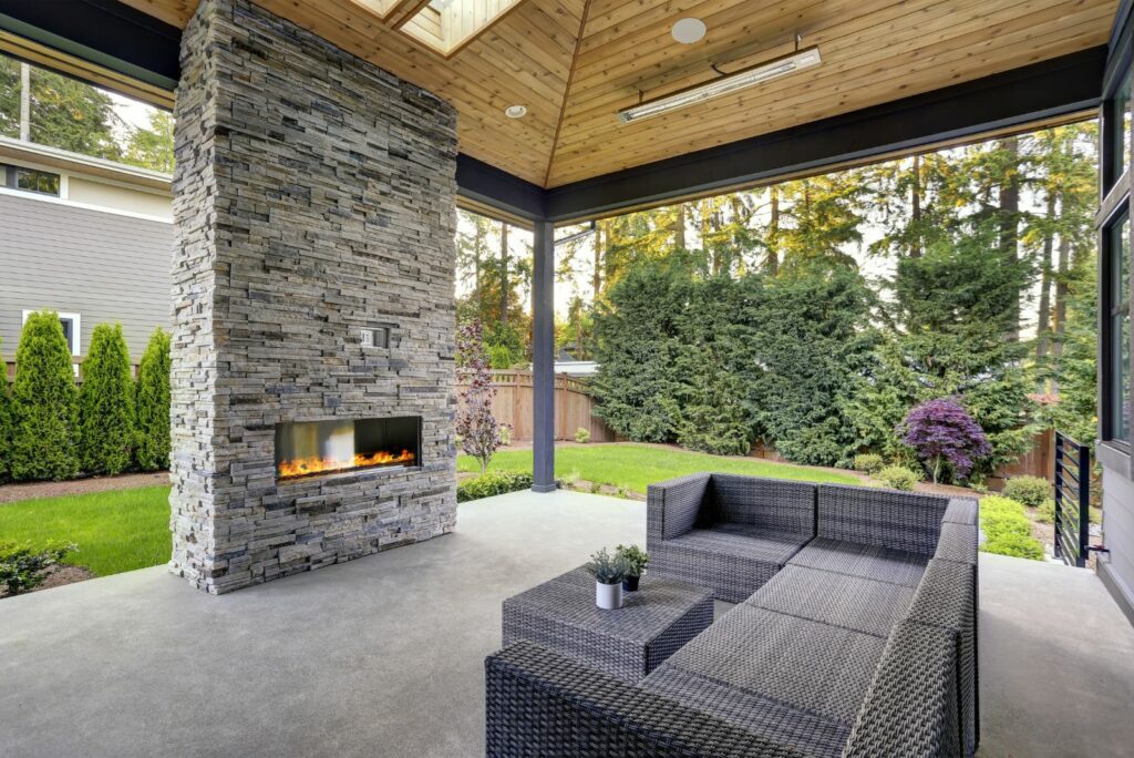 New modern home features a backyard with covered patio accented with stone fireplace