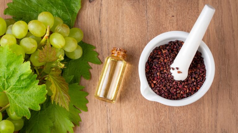 Grape seed oil in small bottle and bunch of grapes together.