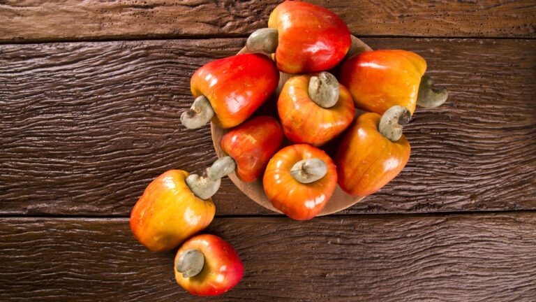 Some cashew fruit over a wooden surface.