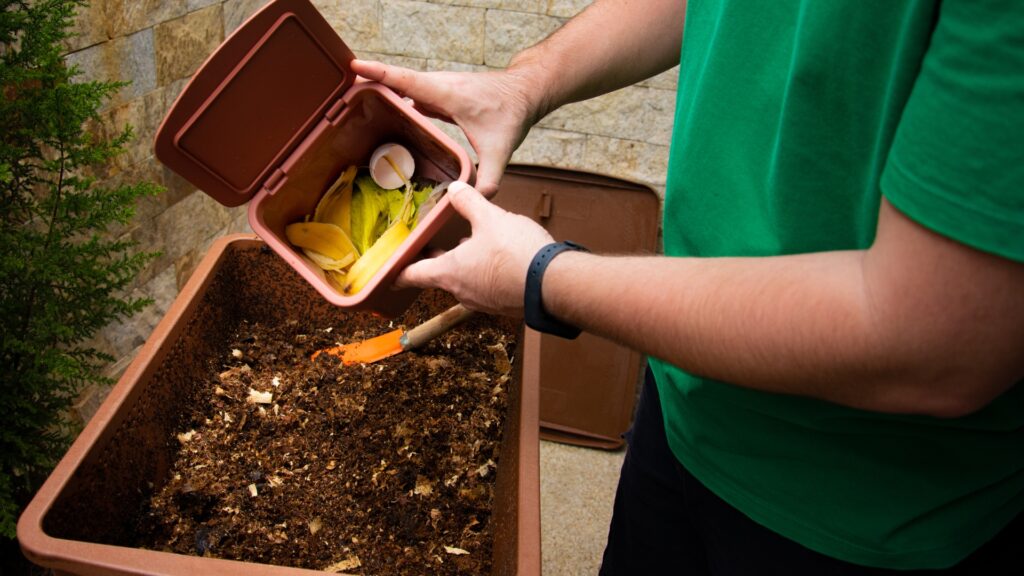gardener throwing kitchen scraps on a compost pile