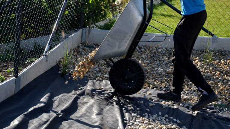 landscaper adds gravel on the landscape fabric for weed prevention