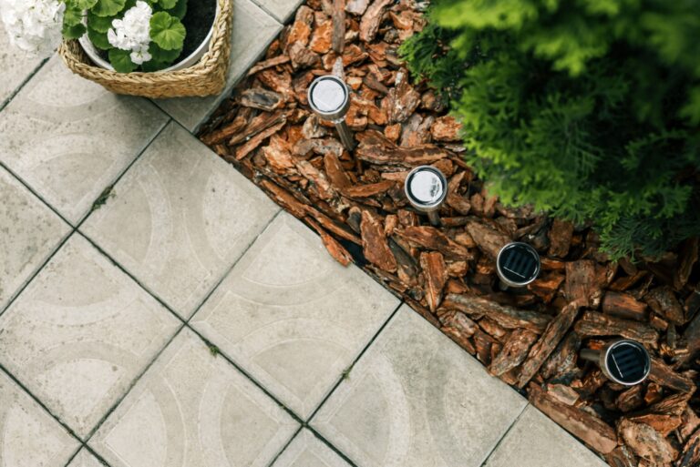 Set of four stainless steel solar garden lights installed in a landscaped outdoor area