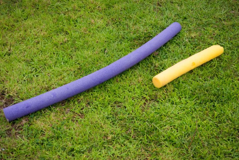 Purple and yellow pool noodles on green grass