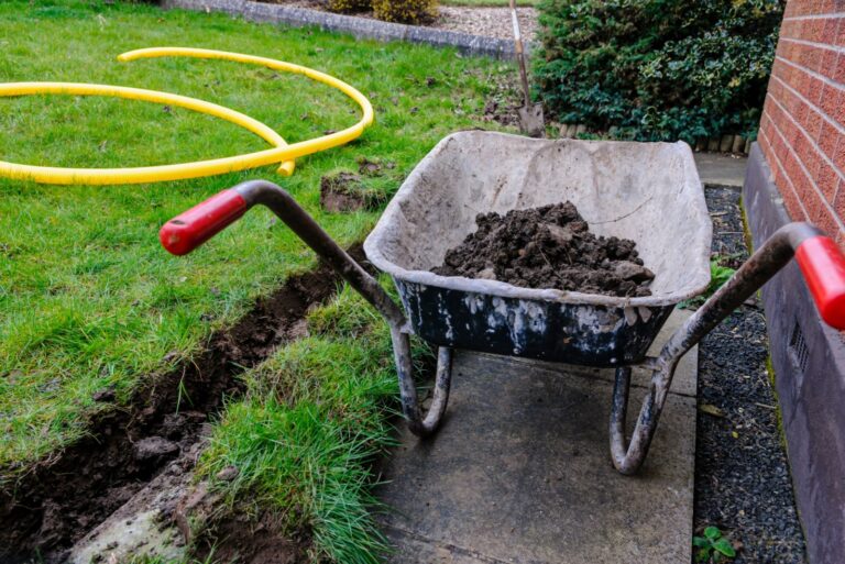 wheelbarrow with soil next to a french drain