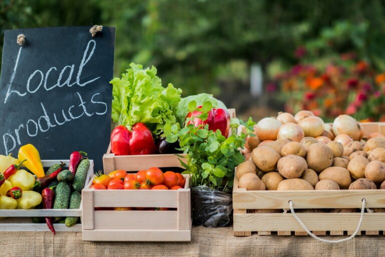 Counter with fresh vegetables and a sign of local products