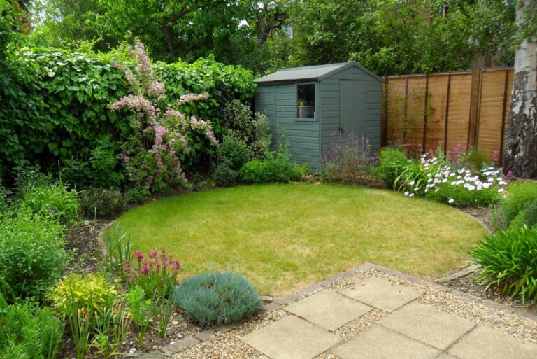Cottage garden with circular lawn, flower beds, paving stones and shed
