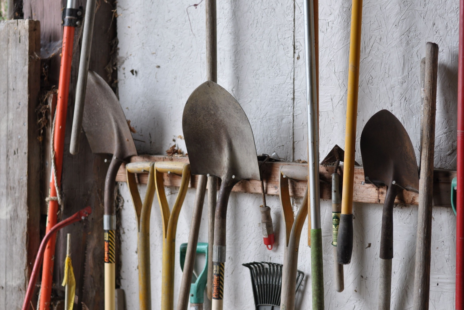 Set of garden tools in a shed leaning up against the wall