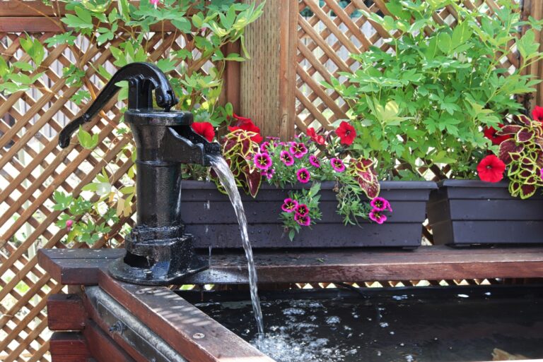 water fountain in front of a lattice with annuals