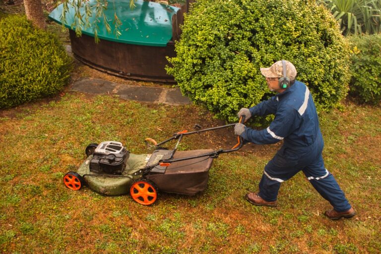 Yard worker mowing grass with lawn mower