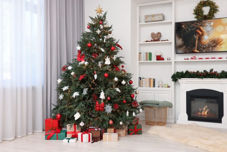 Beautifully decorated Christmas tree near fireplace in room