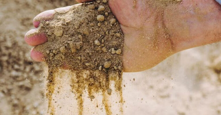 hand adding gypsum to soil