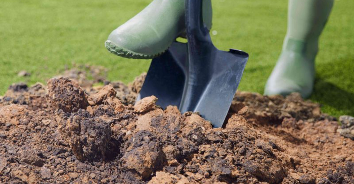 person in boots pushing shovel into soil
